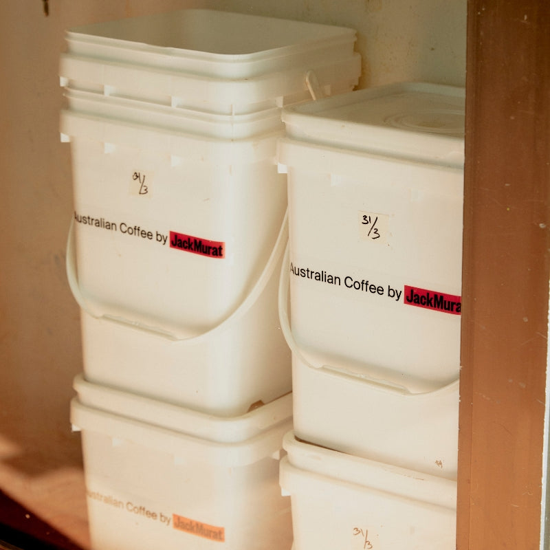 Stacked buckets of Jack Murat roasted coffee in storage